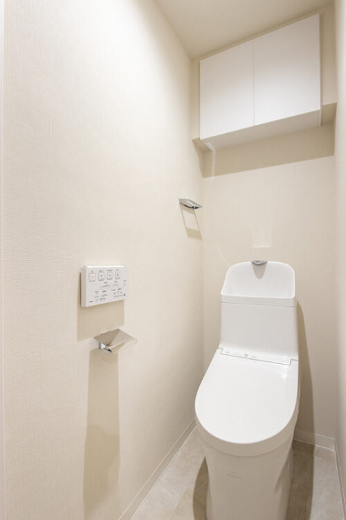 TOTO製ウォシュレット機能付トイレを新規交換しました。収納力のある吊戸棚設置で、トイレットペーパーや掃除用品をすっきり収納可能です。
